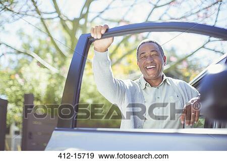 Stock Photo - Portrait of happy senior man leaning on car door. Fotosearch