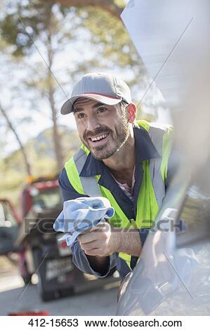Stock Image - Roadside mechanic leaning on car. Fotosearch