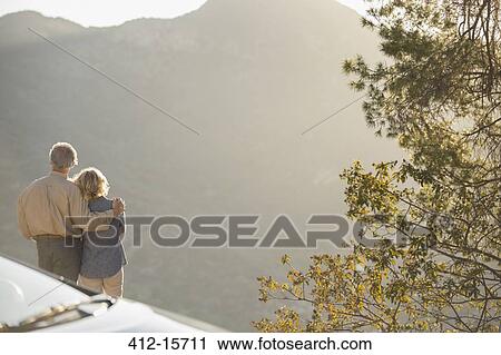 Senior couple looking at mountain view outside car View Large Photo Image Stock Image - Senior couple looking at mountain view outside car. Fotosearch