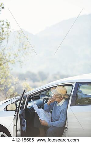 Stock Photography - Senior man checking map in car. Fotosearch