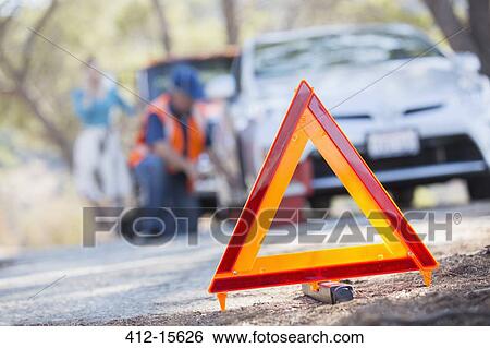 Warning triangle on road with mechanic in background View Large Photo Image Stock Photograph - Warning triangle on road with mechanic in background. Fotosearch