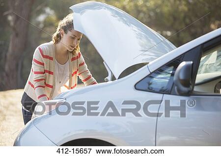 Woman checking car engine at roadside View Large Photo Image Stock Photo - Woman checking car engine at roadside. Fotosearch