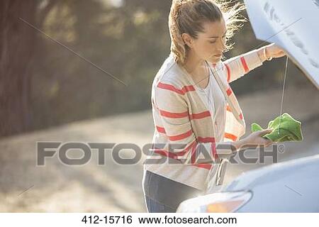 Woman checking oil under automobile hood at roadside View Large Photo Image Stock Photograph - Woman checking oil under automobile hood at roadside. Fotosearch