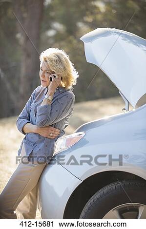 Woman talking on cell phone with automobile hood raised at roadside View Large Photo Image Stock Image - Woman talking on cell phone with automobile hood raised at roadside. Fotosearch