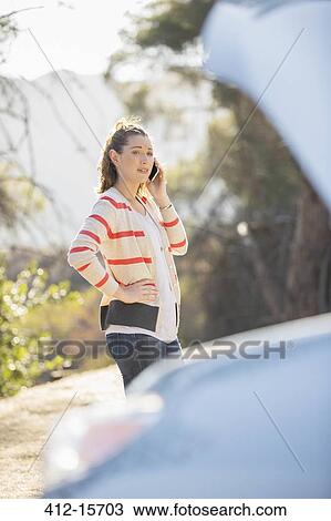 Woman talking on cell phone with automobile hood raised at roadside View Large Photo Image Stock Image - Woman talking on cell phone with automobile hood raised at roadside. Fotosearch
