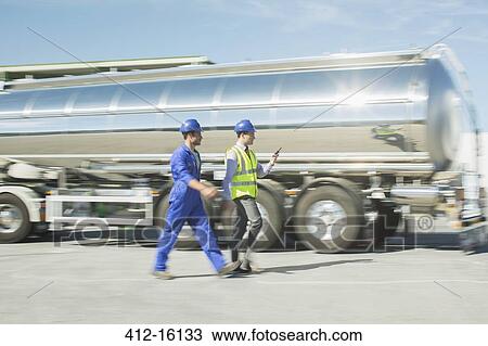 Businessman and worker walking along stainless steel milk tanker View Large Photo Image Stock Image - Businessman and worker walking along stainless steel milk tanker. Fotosearch