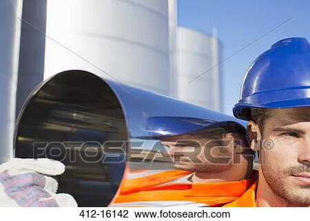 Stock Image - Close up of worker carrying stainless steel tube. Fotosearch
