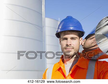 Stock Photo - Close up portrait of worker carrying stainless steel tube. Fotosearch