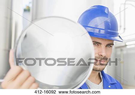 Stock Image - Portrait of confident worker holding stainless steel tube. Fotosearch