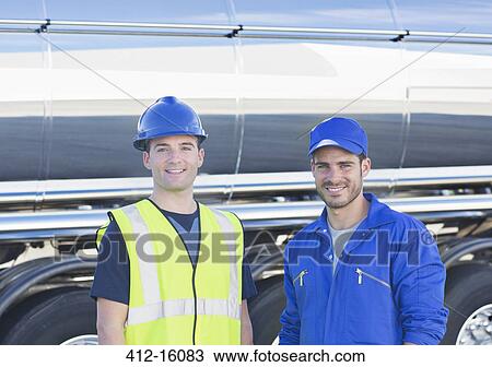 Stock Image - Portrait of confident workers next to stainless steel milk tanker. Fotosearch