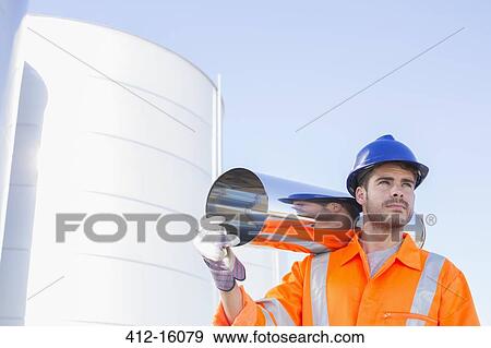 Worker carrying stainless steel tube near silage storage tower View Large Photo Image Stock Photo - Worker carrying stainless steel tube near silage storage tower. Fotosearch