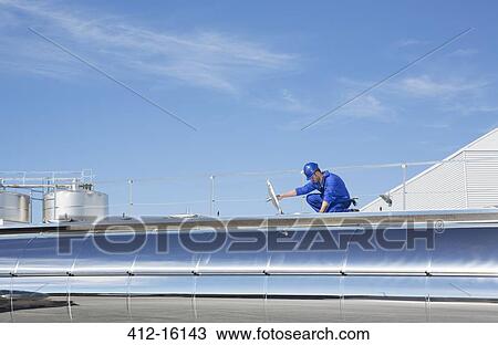 Stock Image - Worker on platform above stainless steel milk tanker. Fotosearch