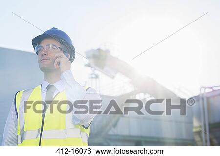 Worker talking on cell phone at granary View Large Photo Image Stock Photograph - Worker talking on cell phone at granary. Fotosearch