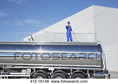 Worker talking on cell phone on platform above stainless steel milk tanker View Large Photo Image Stock Photo - Worker talking on cell phone on platform above stainless steel milk tanker. Fotosearch