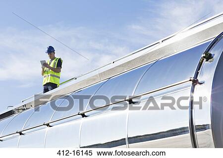 Worker using digital tablet on platform above stainless steel milk tanker View Large Photo Image Stock Photography - Worker using digital tablet on platform above stainless steel milk tanker. Fotosearch