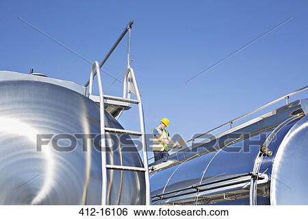 Worker using laptop on platform above stainless steel milk tanker View Large Photo Image Stock Photograph - Worker using laptop on platform above stainless steel milk tanker. Fotosearch