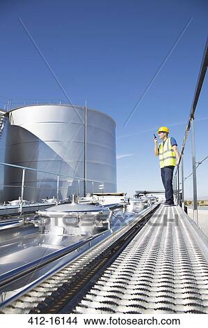 Worker using walkie-talkie on platform above stainless still milk tanker View Large Photo Image Picture - Worker using walkie-talkie on platform above stainless still milk tanker. Fotosearch