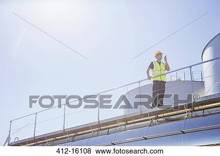 Worker using walkie-talkie on platform next to silage storage towers View Large Photo Image Stock Photo - Worker using walkie-talkie on platform next to silage storage towers. Fotosearch