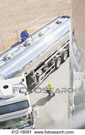 Stock Image - Workers around stainless steel milk tanker. Fotosearch
