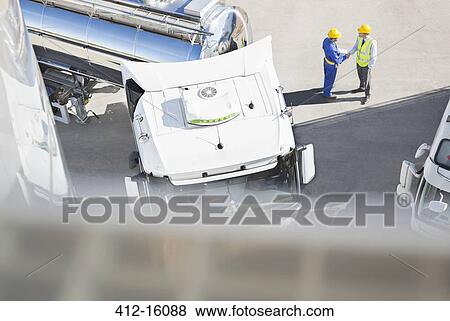 Workers handshaking next to stainless steel milk tanker View Large Photo Image Stock Photo - Workers handshaking next to stainless steel milk tanker. Fotosearch