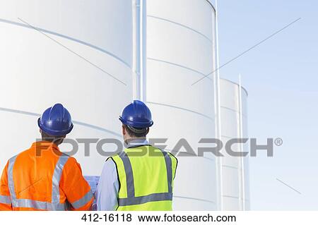 Workers looking up at silage storage towers View Large Photo Image Stock Photo - Workers looking up at silage storage towers. Fotosearch