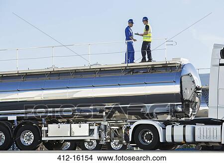 Picture - Workers on platform above stainless steel milk tanker. Fotosearch