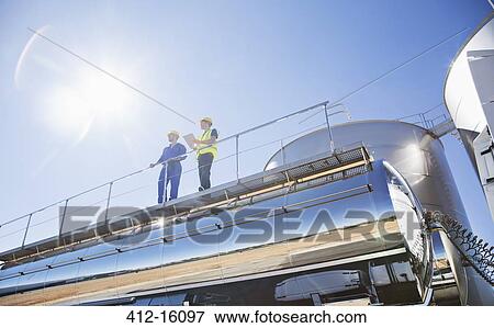 Stock Photo - Workers on platform above stainless steel milk tanker. Fotosearch