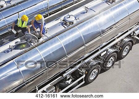 Stock Image - Workers on top of stainless steel milk tanker. Fotosearch