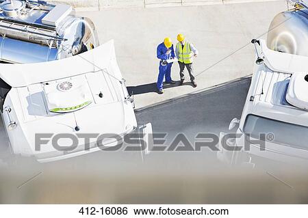 Workers reviewing paperwork near milk tankers View Large Photo Image Stock Photograph - Workers reviewing paperwork near milk tankers. Fotosearch