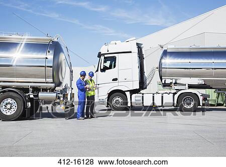 Stock Photo - Workers talking next to stainless steel milk tankers. Fotosearch