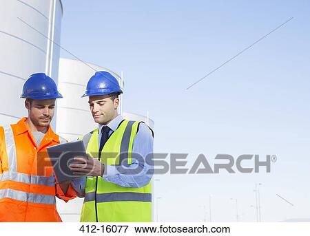 Workers using digital tablet near silage storage towers View Large Photo Image Stock Photo - Workers using digital tablet near silage storage towers. Fotosearch