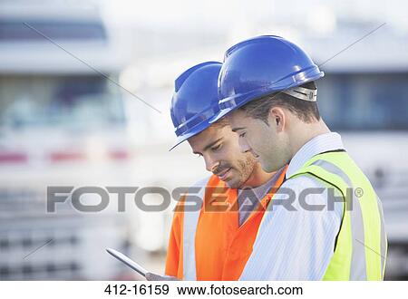 Workers using digital tablet near trucks View Large Photo Image Stock Photo - Workers using digital tablet near trucks. Fotosearch