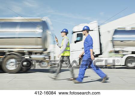 Workers walking past stainless steel milk tankers View Large Photo Image Picture - Workers walking past stainless steel milk tankers. Fotosearch