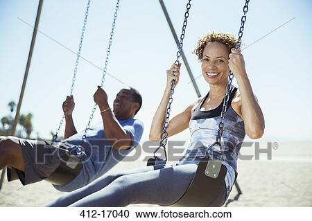 Couple on swings at beach View Large Photo Image Stock Image - Couple on swings at beach. Fotosearch