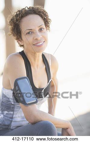 Portrait of confident female jogger wearing arm band View Large Photo Image Stock Image - Portrait of confident female jogger wearing arm band. Fotosearch