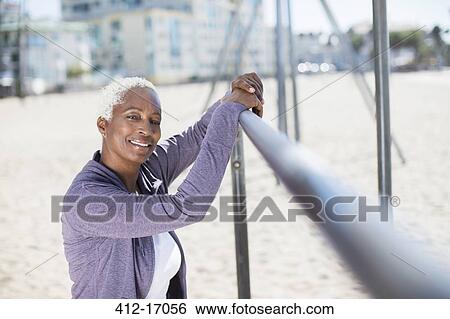 Portrait of confident woman leaning on bar at beach playground View Large Photo Image Stock Photograph - Portrait of confident woman leaning on bar at beach playground. Fotosearch
