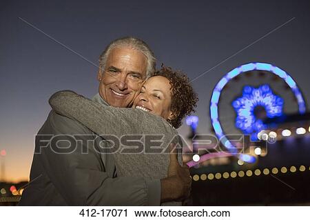 Portrait of couple hugging outside amusement park at night View Large Photo Image Stock Image - Portrait of couple hugging outside amusement park at night. Fotosearch