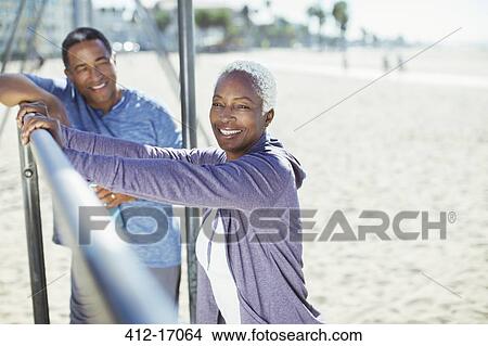 Portrait of senior couple leaning on bar at beach playground View Large Photo Image Picture - Portrait of senior couple leaning on bar at beach playground. Fotosearch