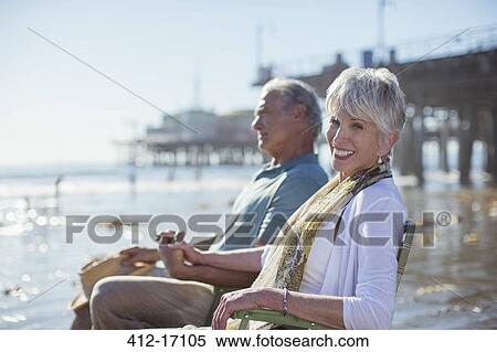 Stock Photography - Portrait of senior couple relaxing in lawn chairs on beach. Fotosearch