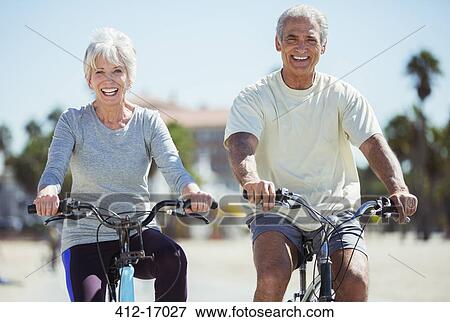 Stock Photo - Portrait of senior couple riding bicycles on beach. Fotosearch