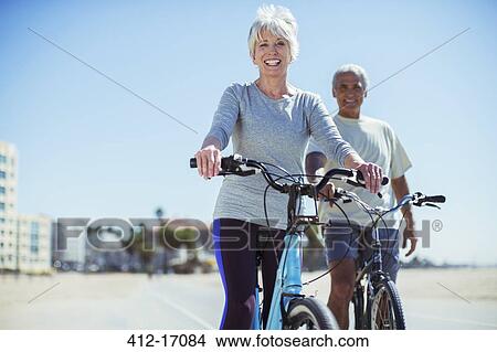Portrait of senior couple with bicycles on beach boardwalk View Large Photo Image Picture - Portrait of senior couple with bicycles on beach boardwalk. Fotosearch