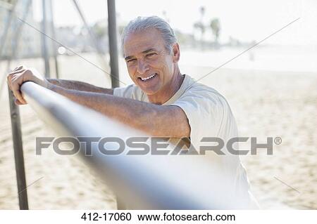 Portrait of senior man leaning on bar at beach View Large Photo Image Stock Image - Portrait of senior man leaning on bar at beach. Fotosearch