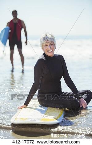 Portrait of senior woman on surfboard at beach View Large Photo Image Stock Image - Portrait of senior woman on surfboard at beach. Fotosearch