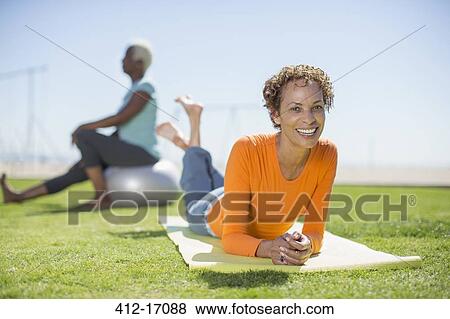 Portrait of smiling woman on yoga mat in park View Large Photo Image Stock Photo - Portrait of smiling woman on yoga mat in park. Fotosearch