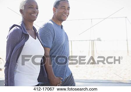 Stock Photo - Senior couple holding hands and walking. Fotosearch