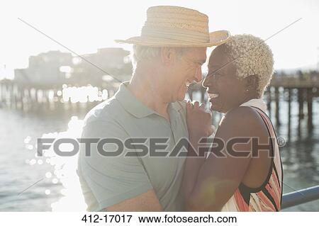 Stock Photo - Senior couple hugging on pier. Fotosearch