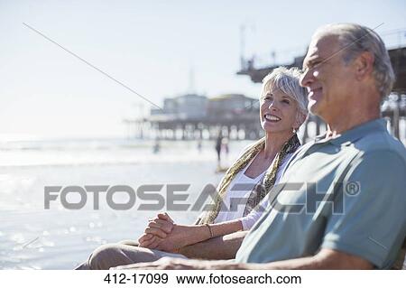 Stock Photo - Senior couple relaxing on sunny beach. Fotosearch