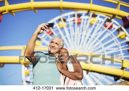 Senior couple taking selfie at amusement park View Large Photo Image Stock Image - Senior couple taking selfie at amusement park. Fotosearch