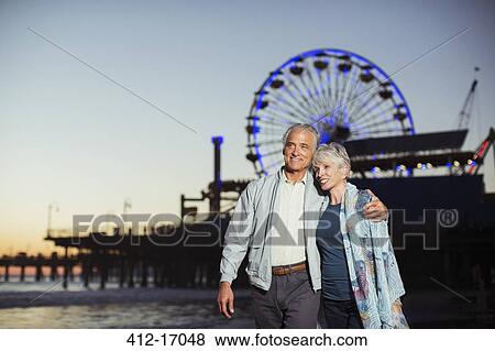 Stock Photo - Senior couple walking on beach at night. Fotosearch