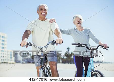 Stock Photograph - Senior couple with bicycles on beach. Fotosearch